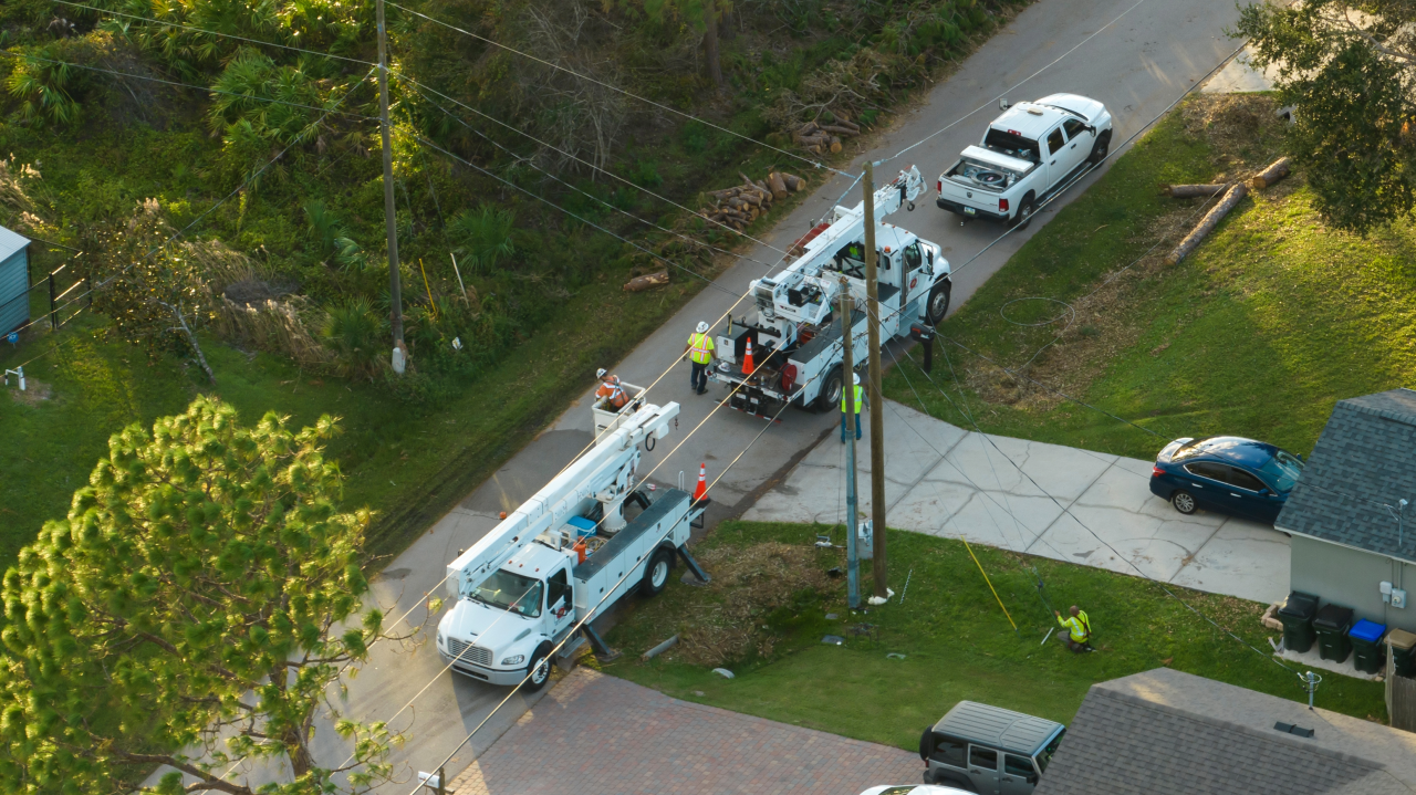 Aerial view of utility crew repairing power lines after storm damage, illustrating why off-grid battery storage and emergency power resilience are essential for critical operations
