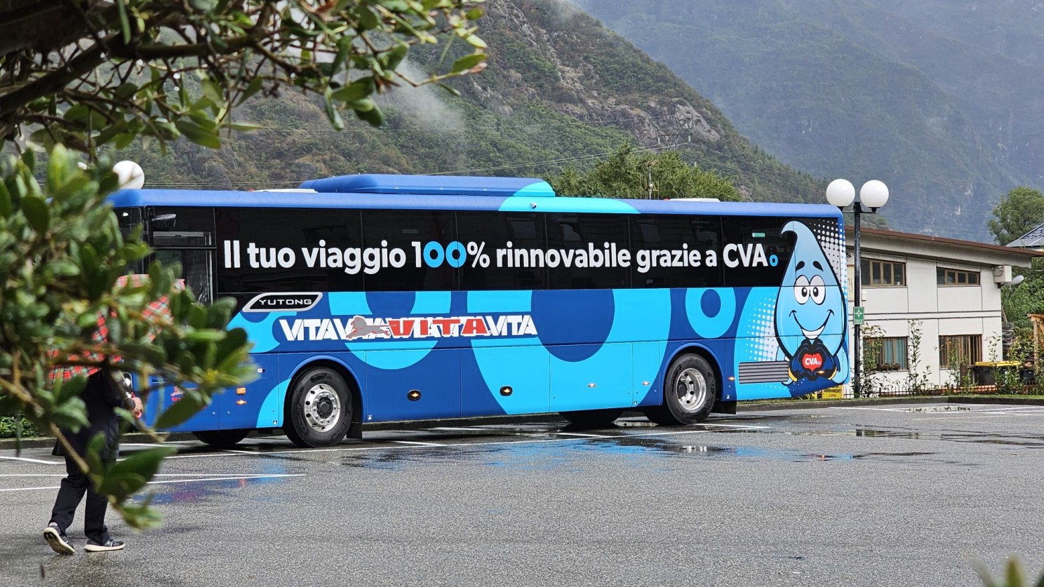Yutong electric bus with VITA-CVA branding showing 'Il tuo viaggio 100% rinnovabile grazie a CVA' in the Alpine landscape of Valle d'Aosta, representing 100% renewable public transport
