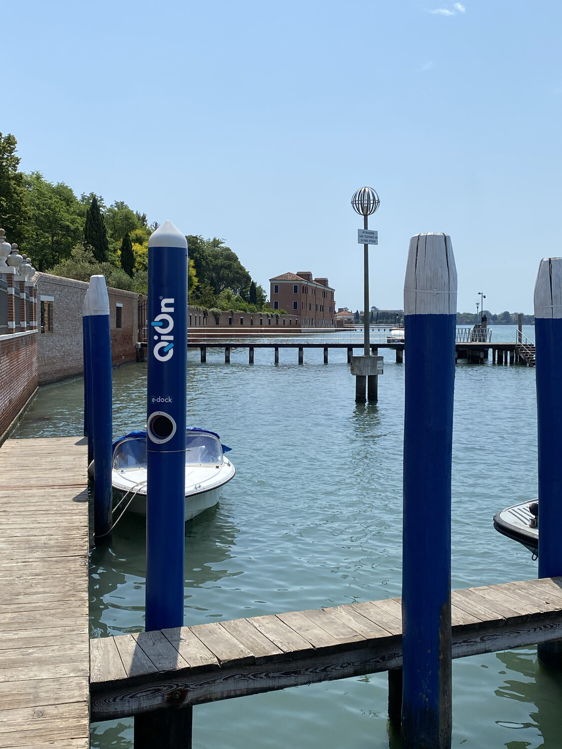QiOn E-Dock blue mooring poles at a marina dock with small electric boats moored alongside, showing real-world port electrification and marine EV charging deployment