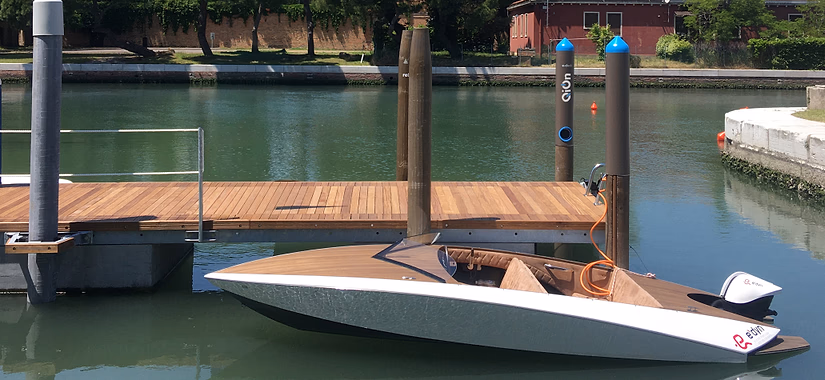 QiOn E-Dock electrified mooring pole installed at a Venice lagoon waterfront dock, styled as a traditional Venetian striped palina for electric boat and vessel charging