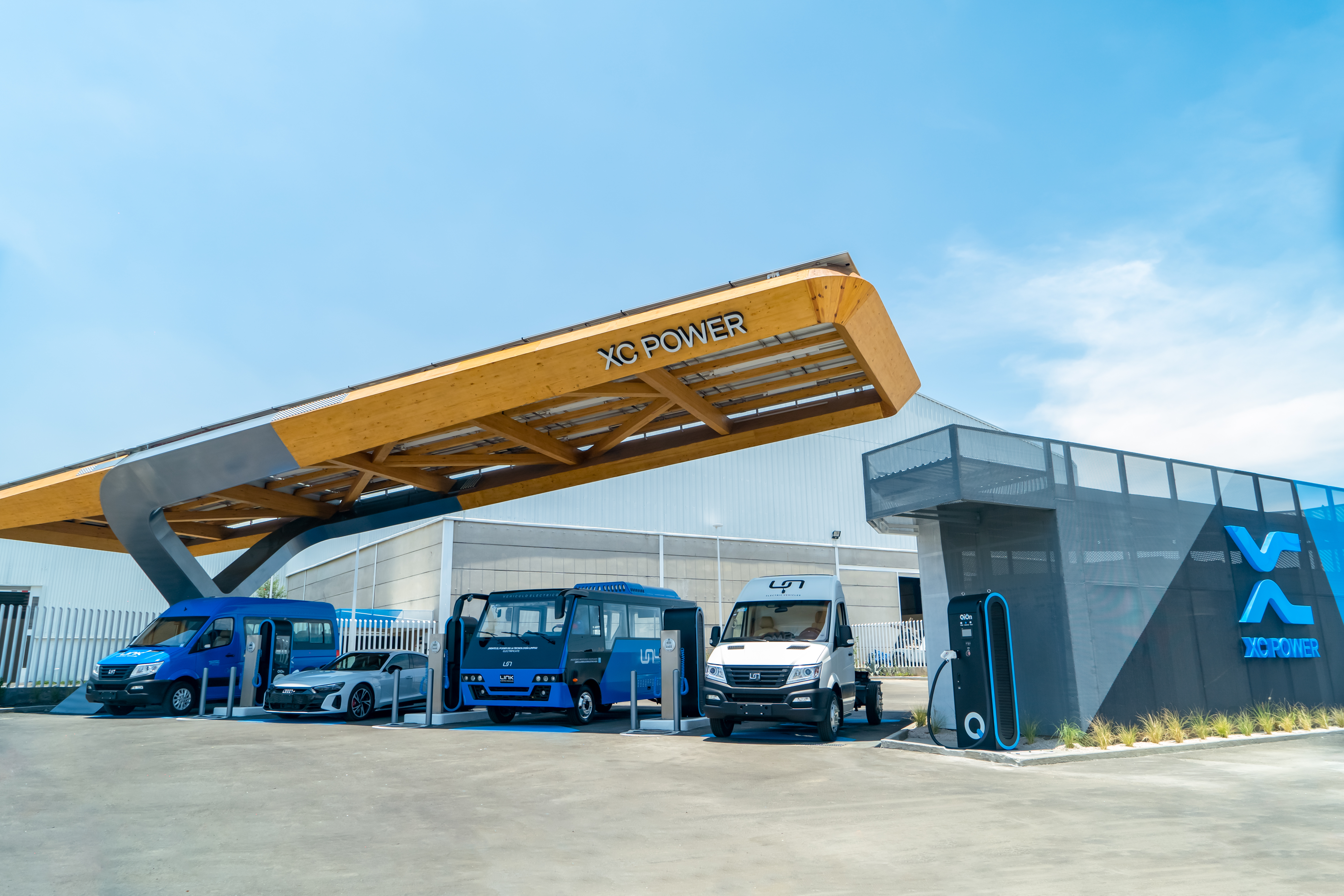 XC Power laminated wood canopy with solar panels over electric vans, buses and trucks charging at QiOn–XC Power Supercool Mobility Center in Puebla, Mexico — world's first public megawatt EV charging station